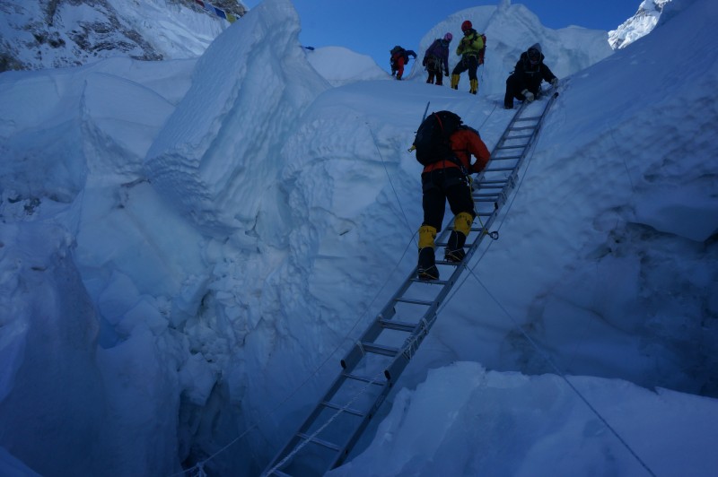 LC descends three ladders lashed together, crossing a deep dark crevasse.  (Photo: Justin Merle)