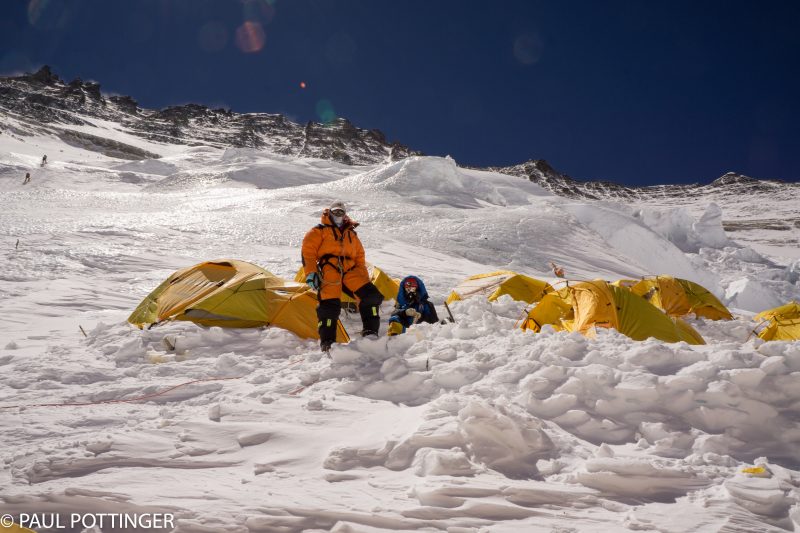 Ramin and his Sherpa guide look down from the middle row of tents at Upper Camp 3. Climbers on the route seen upper left.